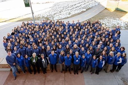 A large group of people at the 19th annual International Animal Welfare Judging and Assessment Contest stand next to each other and look up at the camera for a group photo.