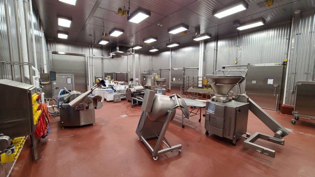 Various pieces of meat processing equipment are spread throughout the processing room waiting to be moved into their final positions and fully set-up.