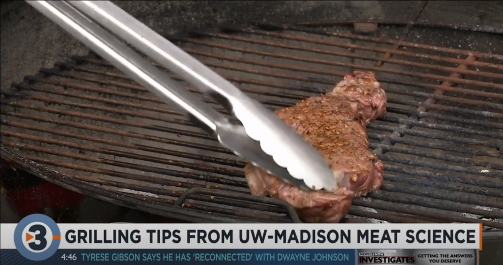 A screenshot from a Channel 3000 TV broadcast showing a piece of meat on a charcoal grill with a caption that reads: Grilling Tips From UW-Madison Meat Science.