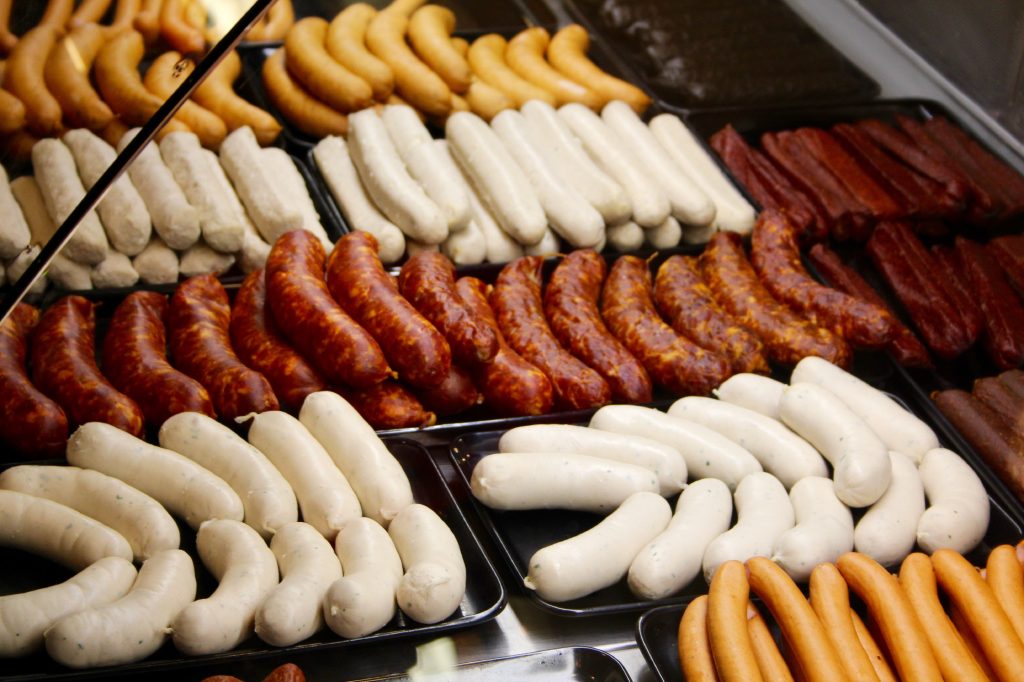 An assortment of different colored sausages on trays.