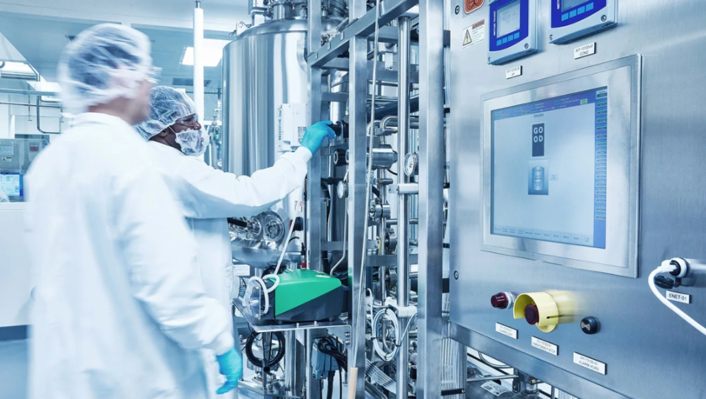 Two people in white lab coats and hairnets stand in front of stainless-steel equipment in Eat Just Inc’s Good Meat pilot plant.