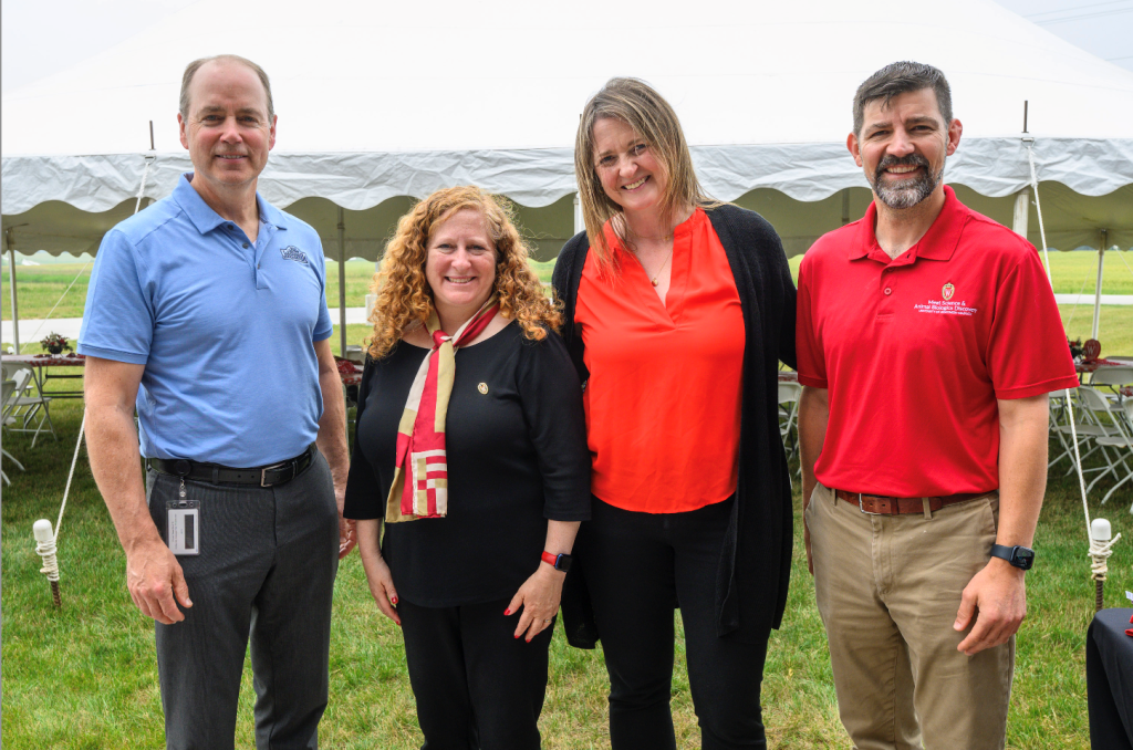 Kevin Ladwig, UW-Madison Chancellor Jennifer Mnookin, and Dr. Jeff Sindelar stand with another woman stand outside a tent at a brat cookout.