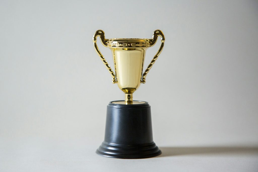 A gold cup trophy with handles on both sides and a black base.